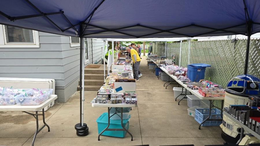 Long tables of merchandise lined up beneath a canopy beside the house