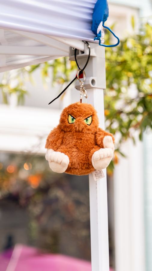 A small cryptid plush hanging from a vendor tent