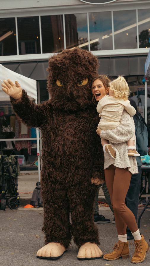 Bigfoot waving as a child laughs