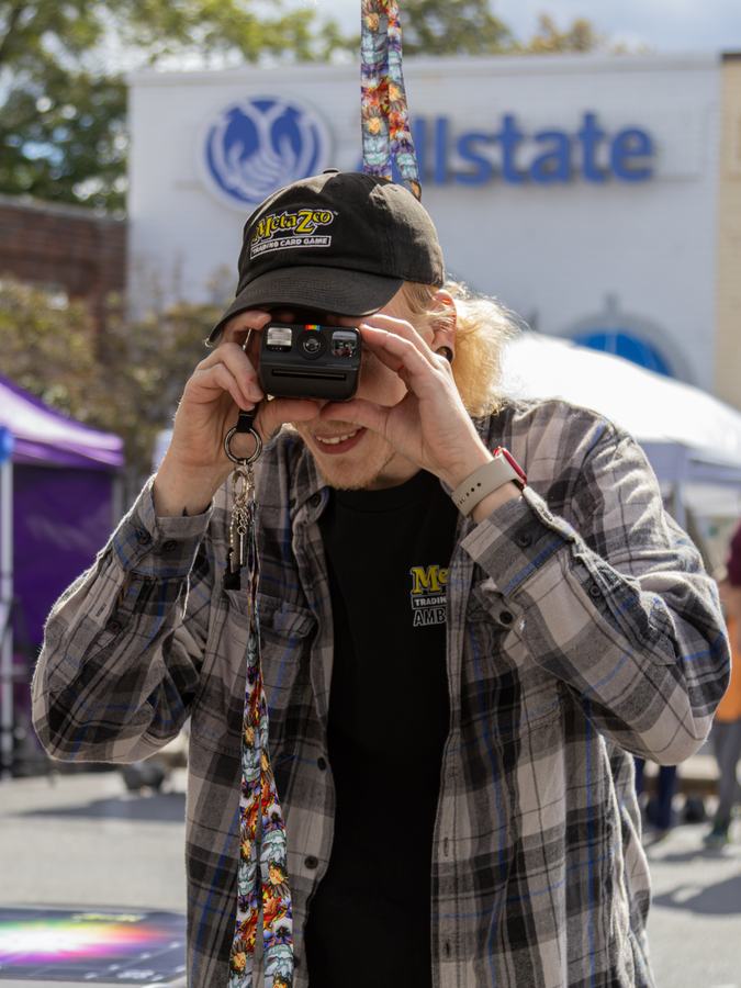 A photographer in a MetaZoo cap behind a vintage camera