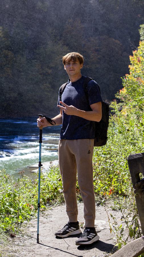 A hiker with trekking poles above the river