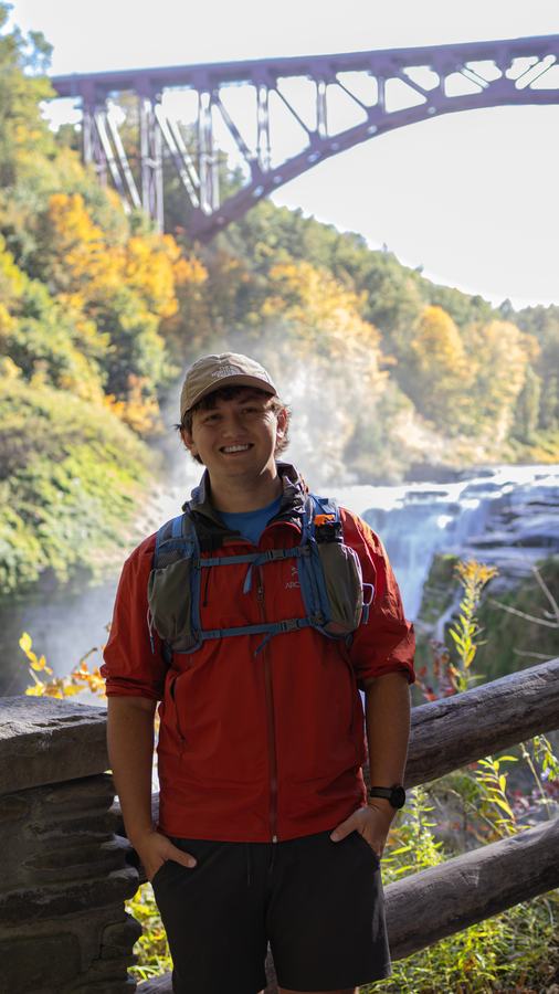 A hiker in red at the stone railing below the bridge