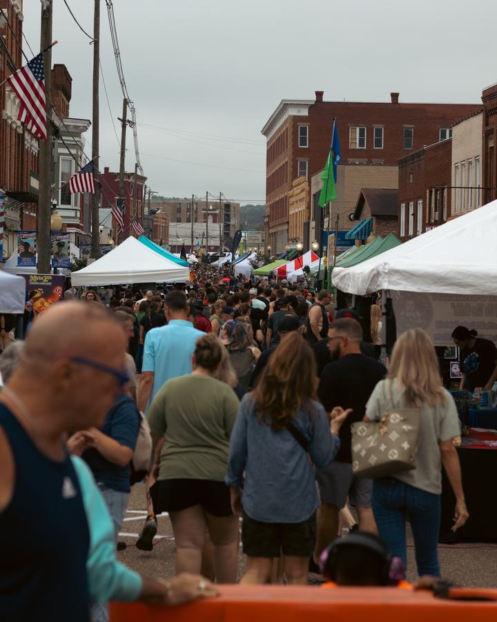 Crowds filling the festival street between brick storefronts