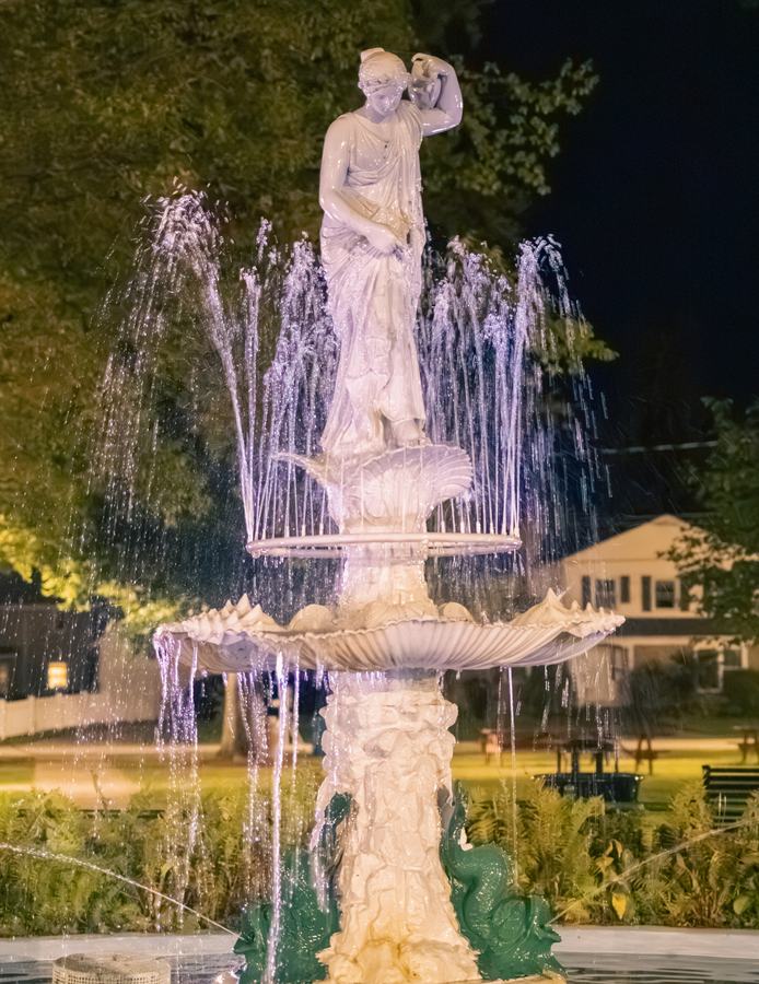 A lit fountain statue at night