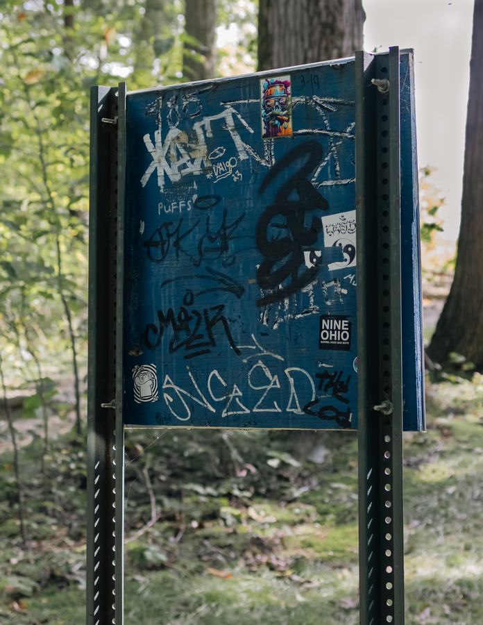 A graffiti-covered trail sign in the woods